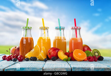 Verres de jus frais avec mélange de fruits placés sur des planches. Ciel bleu sur l'arrière-plan. Concept de boissons saines, un des antioxydants Banque D'Images