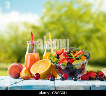 Verres de jus frais et de salade avec mélange de fruits placés sur des planches sur le jardin. blur background. Concept d'une saine alimentation, un Banque D'Images