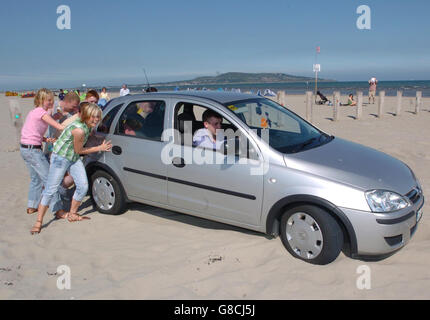 Les membres du public qui cherchent du soleil tentent de pousser une voiture de mans hors du sable mou sur l'île de Bull, alors que les températures sur la côte est ont grimpé jusqu'à 18 C dans certaines parties de l'Irlande. Banque D'Images