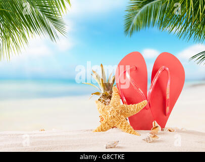 Tongs d'été sur une plage de sable, mer de flou sur l'arrière-plan. Concept de relaxation exotique d'été Banque D'Images