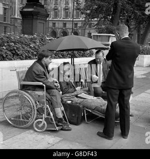 Francis Hetherington (en fauteuil roulant), de Colchester, Essex, et George Clark, de Sloane Square,Londres, jeûnent sur la place du Parlement pour protester contre la guerre du Vietnam.Ils parlent aux députés travaillistes Frank Allaun (face à la caméra, à droite) et Stanley Orme (de retour à la caméra), qui étaient en route pour la Chambre des communes. Banque D'Images