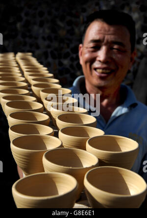 Chengcheng, Province de Shaanxi en Chine. 26 Juin, 2016. Artiste folklorique Liu Zhongyang porte semi bols de porcelaine bleu et blanc dans le Yaotou zone touristique de four dans le Yaotou Canton de Chengcheng, comté du nord-ouest de la Chine, dans la province de Shaanxi, du 26 juin 2016. Le site de l'ancien fours folk, couvrant une superficie de 4 kilomètres carrés, a une histoire de faire des produits céramiques pour plus de mille ans. Les techniques de la céramique en Yaotou Four fut répertorié dans le patrimoine culturel immatériel national en 2006. © Tao Ming/Xinhua/Alamy Live News Banque D'Images