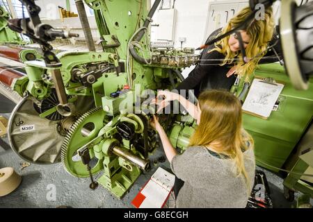 Directeur de la conception et de la production Laylah Cook, 24 ans, en haut, assiste le directeur Juliet Bailey, 33 ans, alors qu'elle change un cog sur un métier à tisser des années 1980, réalisé par Dornier, la même compagnie responsable de la bombe légère allemande de la Seconde Guerre mondiale, le Dornier do 17, au Bristol Weaving Mill, Le premier moulin à papier à Bristol en près de 100 ans, entièrement dirigé par des femmes. Banque D'Images