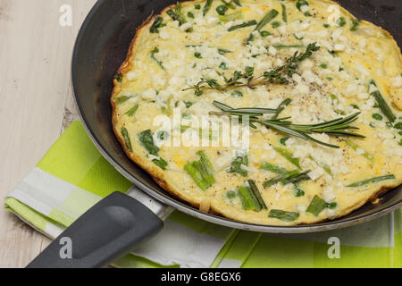 Frittata italienne avec des oignons de printemps et les pois sur une table en bois blanc Banque D'Images