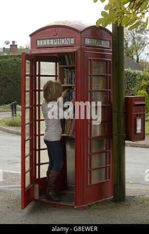 Wendy Hanlon regarde des livres dans une boîte téléphonique rouge qui a été convertie en une minuscule bibliothèque libre d'utilisation dans le village de Wall, dans le Staffordshire. Banque D'Images