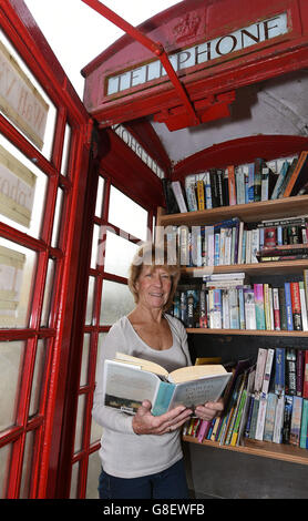 Wendy Hanlon regarde des livres dans une boîte téléphonique rouge qui a été convertie en une minuscule bibliothèque libre d'utilisation dans le village de Wall, dans le Staffordshire. Banque D'Images