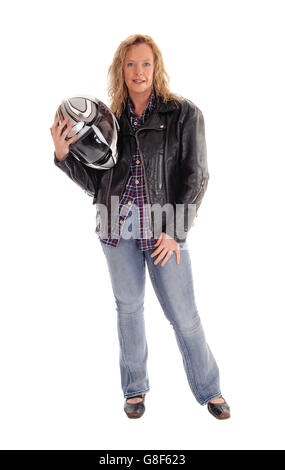 L'âge moyen d'une femme debout en jeans, tenant son casque de moto dans une veste en cuir, isolée pour fond blanc. Banque D'Images