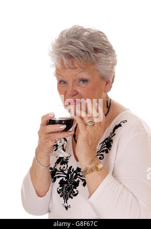 Une belle femme senior dans un chandail beige tenant un verre de vin rouge, isolée pour fond blanc. Banque D'Images