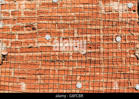 La texture du mur de briques endommagées avec maille d'acier de renfort Banque D'Images