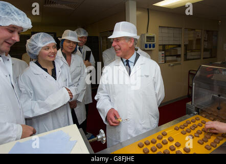 Le Prince de Galles et Cecily Weston (à gauche), fille du président de Charbonnel et Walker, Galvin Weston, décorent des chocolats lors d'une visite de l'usine de chocolat House of Dorchester à Poundbury, Dorset. Banque D'Images