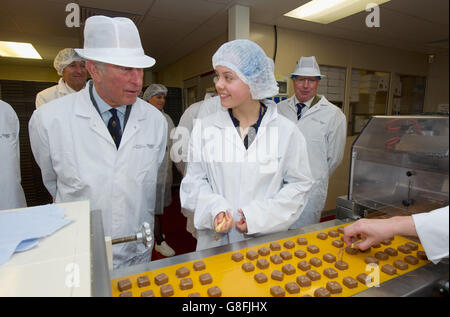 Le Prince de Galles et Cecily Weston (à droite), fille du président de Charbonnel et Walker, Galvin Weston, décorent des chocolats lors d'une visite de l'usine de chocolat House of Dorchester à Poundbury, Dorset. Banque D'Images