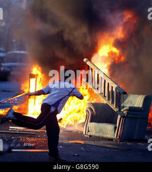 Un enfant jette du bois sur un feu de camp à Belfast. Dans toute l'Irlande du Nord, des centaines de feux de camp seront mis à feu, signalant le début de la plus grande journée de marche dans le calendrier de la commande Orange. Demain, des milliers d'Orangemen partiront dans les rues pour les défilés commémoratifs de la bataille de Boyne. La police et les troupes seront en attente dans le nord de Belfast, où les marcheurs traverseront le district d'Ardoyne à deux reprises. Banque D'Images