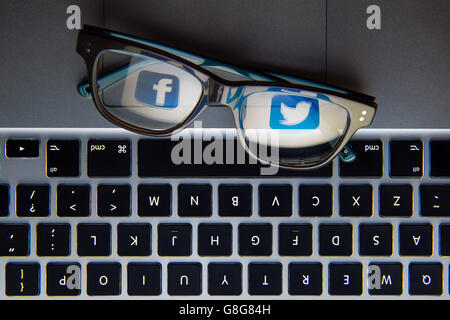 Les logos des sites de réseaux sociaux Facebook et Twitter se reflètent dans une paire de lunettes. Banque D'Images