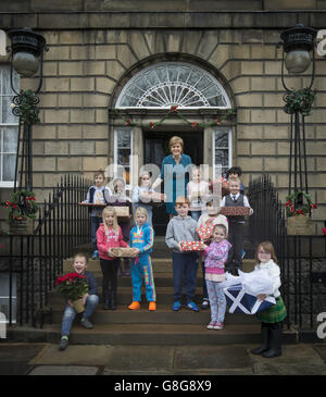 La première ministre écossaise Nicola Sturgeon avec des écoliers de l'école primaire de Forthview à Pilton, alors qu'elle dévoile sa carte de Noël 2015 à sa résidence officielle d'Édimbourg, Bute House. Une illustration festive spéciale de Katie Morag de Mairi Hedderwick présente sur le devant de la carte. Banque D'Images
