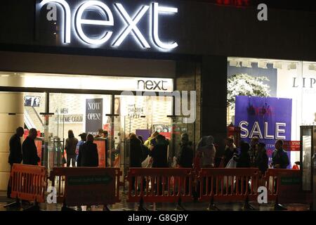 Les clients font la queue sous la pluie pour entrer dans un magasin Next du centre-ville de Liverpool au fur et à mesure que les ventes du lendemain de Noël se font. Banque D'Images