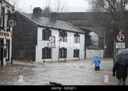 Les gens se sont empais dans les eaux inondées à Mytholmroyd à Caldernon, dans le West Yorkshire, où les sirènes des crues ont été sondées après des averses torrentielles. Banque D'Images