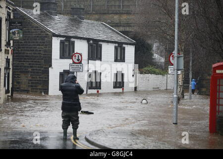 Les gens se sont empais dans les eaux inondées à Mytholmroyd à Caldernon, dans le West Yorkshire, où les sirènes des crues ont été sondées après des averses torrentielles. Banque D'Images