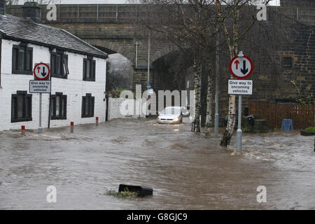 Un véhicule traverse les eaux d'inondation à Mytholmroyd, à Caldove, dans le West Yorkshire, où les sirènes d'inondation ont été sondées après des détrots torrentiels. Banque D'Images