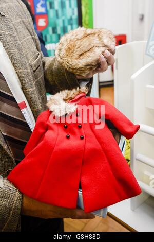 Un manteau rouge et un chapeau de fourrure pour une poupée Bonnie & Pearl qui ont été présentés au duc de Cambridge comme cadeaux pour sa femme et sa fille lors de sa visite à la Saltley Academy à Birmingham. Banque D'Images