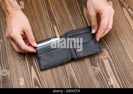 Homme noir portefeuille dans les mains de l'homme sur fond de bois foncé Banque D'Images