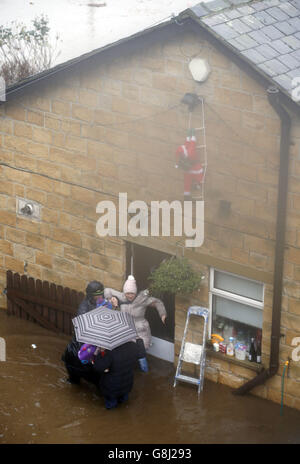 Une femme est aidée d'une maison à Mytholmroyd à Caldove, dans le West Yorkshire, où des sirènes d'inondation ont été sondées après des détrots torrentiels. Banque D'Images