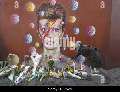 Les fleurs sont laissées sous une fresque de David Bowie sur le mur d'un magasin de Morley à Brixton, Londres, le lieu de naissance des chanteurs, après la mort de la rock star après une bataille de 18 mois contre le cancer. Banque D'Images