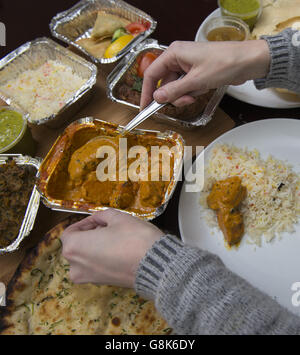 Un curry de poulet est servi entouré de plats indiens à emporter. Banque D'Images