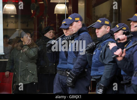 Les clients regardent depuis l'intérieur d'un restaurant Burger King dans le centre-ville de Dublin tandis que les membres de l'unité d'ordre public de Garda affrontent des manifestants anti-racisme lors d'une contre-manifestation contre le lancement d'une branche irlandaise de Pegida, le mouvement d'extrême-droite en provenance d'Allemagne. Banque D'Images