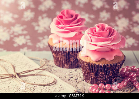 Cupcakes avec sweet rose des fleurs et une lettre Banque D'Images