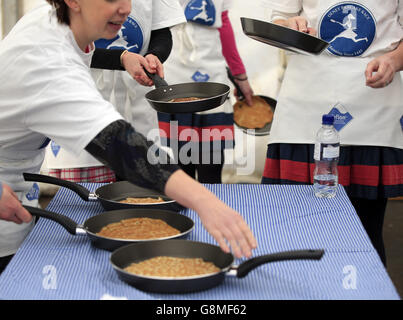 Les concurrents s'emparer de leurs casseroles et crêpes avant la course annuelle de crêpes Shrove Tuesday à Olney, Buckinghamshire. Banque D'Images