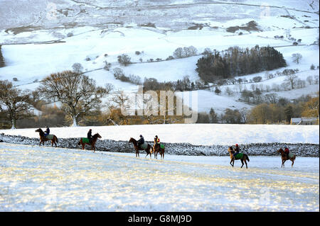 Collines enneigées à travers Coverdale dans les Yorkshire Dales tandis que les chevaux et leurs cavaliers se rendent aux galops sur Middleham Moor après une chute de neige de nuit. Banque D'Images