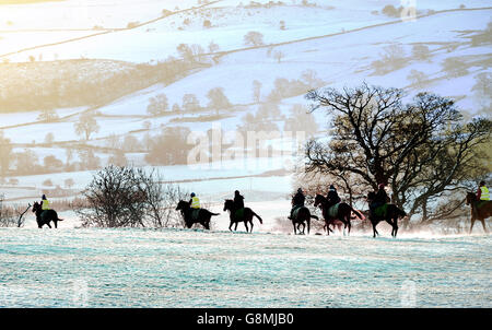 Collines enneigées à travers Coverdale dans les Yorkshire Dales tandis que les chevaux et leurs cavaliers se rendent aux galops sur Middleham Moor après une chute de neige de nuit. Banque D'Images