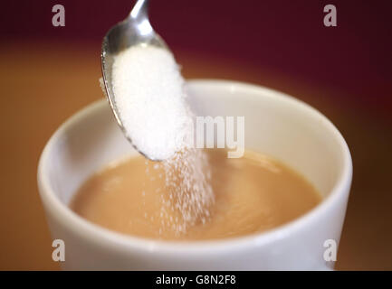 Une cuillère à café de sucre est versée dans une tasse de thé car il y a des quantités de sucre « de lait » trouvées dans un certain nombre de boissons chaudes régulièrement achetées dans les rues hautes de Grande-Bretagne, action on Sugar a dit. Banque D'Images