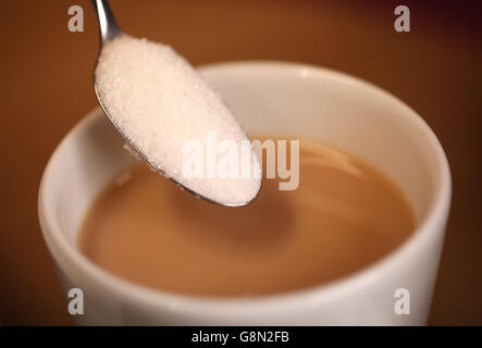 Une cuillère à café de sucre est versée dans une tasse de thé car il y a des quantités de sucre « de lait » trouvées dans un certain nombre de boissons chaudes régulièrement achetées dans les rues hautes de Grande-Bretagne, action on Sugar a dit. Banque D'Images