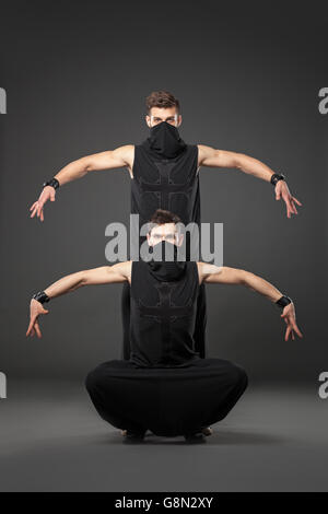 Deux danseurs en costumes de danse ninja contre fond gris. Banque D'Images