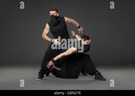 Deux danseurs en costumes de danse ninja contre fond gris. Banque D'Images