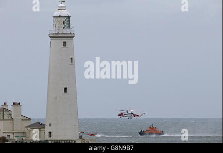 Les équipages de bateaux de sauvetage de RNLI Blyth et RNLI Tynemouth et un hélicoptère de recherche et sauvetage (SAR) de Coastguard basé à l'aéroport de Prestwick passent le phare de St Mary à Whitley Bay pendant un exercice d'entraînement en mer du Nord. Banque D'Images