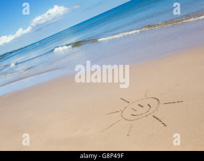 Smiley soleil de face dessin sur une plage. UK Banque D'Images