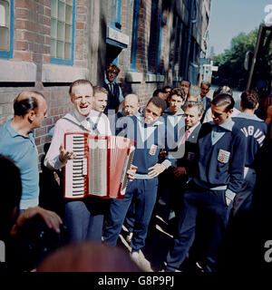 Football - coupe du monde Angleterre 1966 - Uruguay Training - Hillsborough.Les uruguayens Julio Cortes (c) et Luis Ramos (r) sont intrigués par un joueur d'accordéon local qui attend de monter à bord de l'entraîneur de l'équipe Banque D'Images