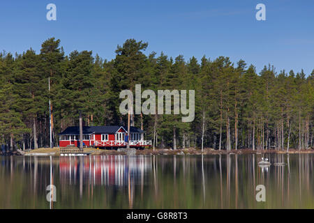 Rouge suédois chalet en bois le long du lac au printemps, dalarna, Suède Banque D'Images