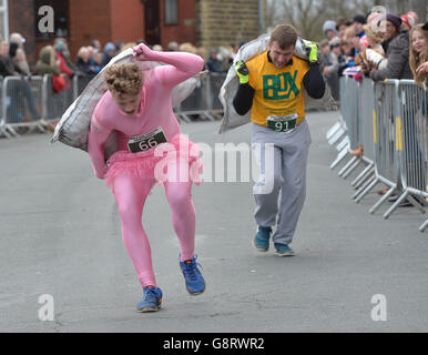 Un concurrent dépose son sac de charbon pendant qu'il se présente à la ligne d'arrivée lors des championnats du monde de transport du charbon à Gawthorpe, dans le West Yorkshire. Banque D'Images