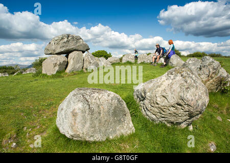 L'Irlande, Sligo, cimetière mégalithique de Carrowmore, couple assis sur stone circle autour de dolmen Banque D'Images