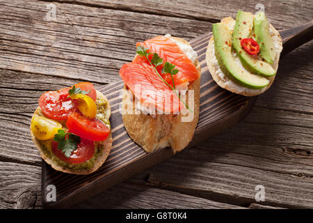 Sandwichs de pain grillé avec de l'avocat, les tomates et le saumon sur fond de bois Banque D'Images