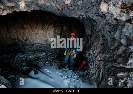Guide de montagne avec casque et sac à dos debout dans cave Banque D'Images