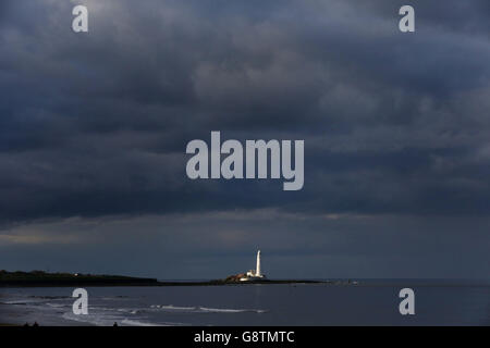 Le phare de St Mary's, dans la baie de Whitely, est éclairé par le soleil du soir tandis que des nuages orageux s'y roulent. Banque D'Images