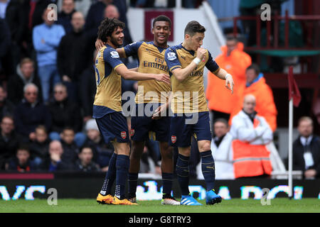 Le Mesut Ozil d'Arsenal (à droite) célèbre le premier but de son équipe avec les coéquipiers Mohamed Elneny (à gauche) et Alex Iwhi (au centre) lors du match de la Barclays Premier League à Upton Park, Londres. Banque D'Images