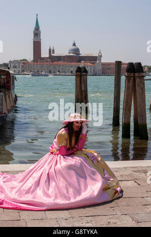 Riva degli Schiavoni, San Marco, Venise : poseur masqué en face du bassin de Saint Marc, et la Chiesa di San Giorgio Maggiore Banque D'Images