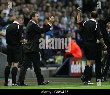 Alain Perrin, directeur de Portsmouth, applaudit sarcastique à l'arbitre Mark Clattenburg (R). Perrin a été congédié du dugout en temps de blessure après avoir critiqué l'arbitre Clatattenburg secondes après que l'officiel ait averti Brian Priske de prendre un jet du mauvais endroit. Banque D'Images