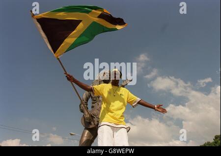 Un fan jamaïcain se tient devant une statue de Bob Marley Banque D'Images