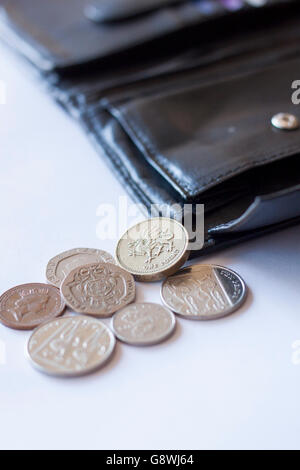 British pound coins spilling out de Etui en cuir noir ouvert Banque D'Images